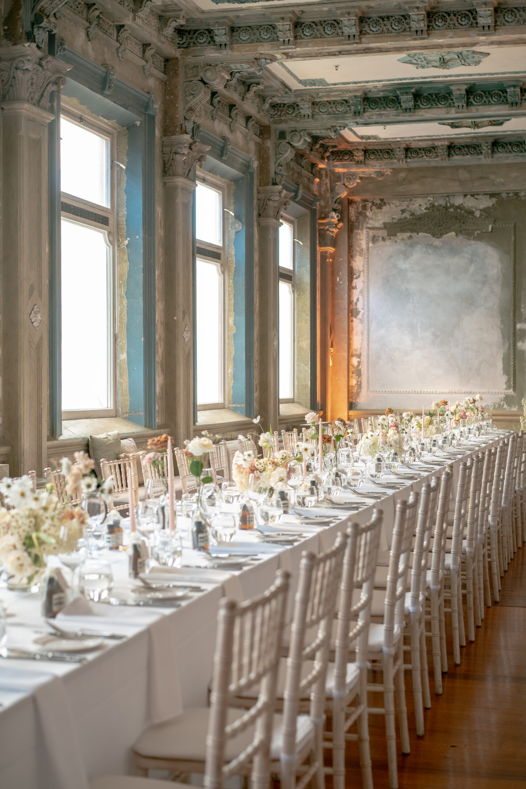 Long table decorated with linen,chairs,candles and ceremony flowers for wedding