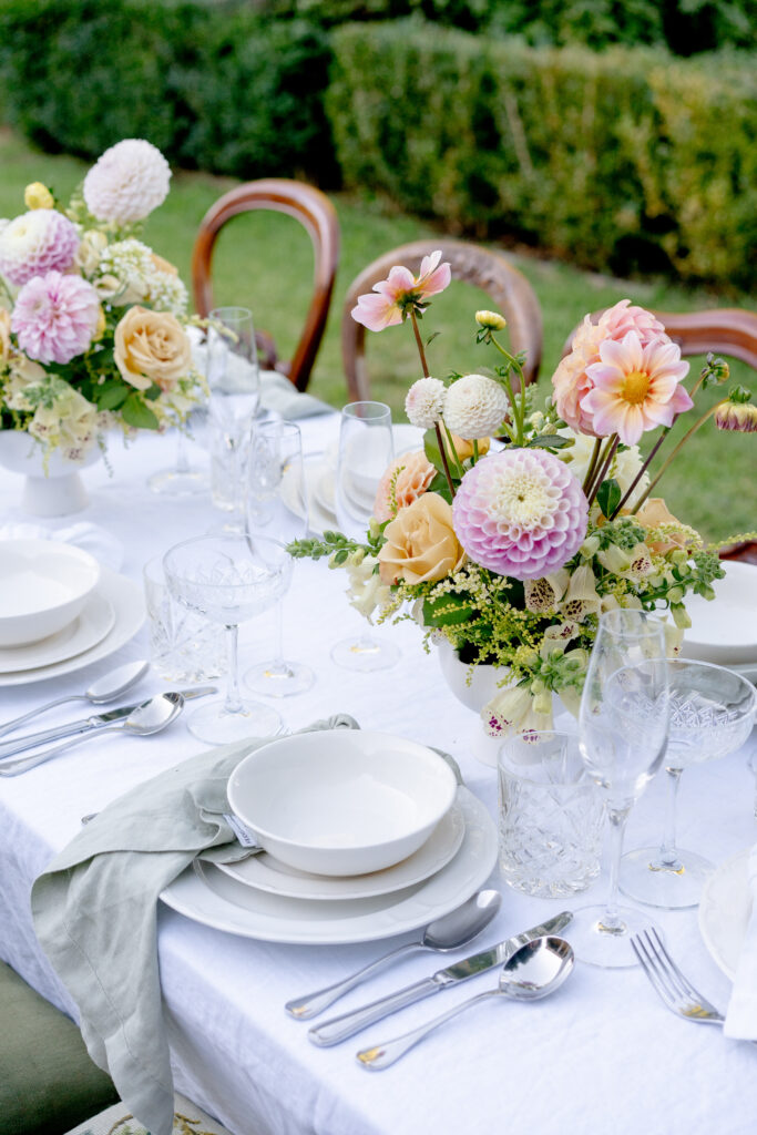 This picture captures an outdoor dining scene, featuring a table adorned with flowers, complemented by neatly arranged chairs.