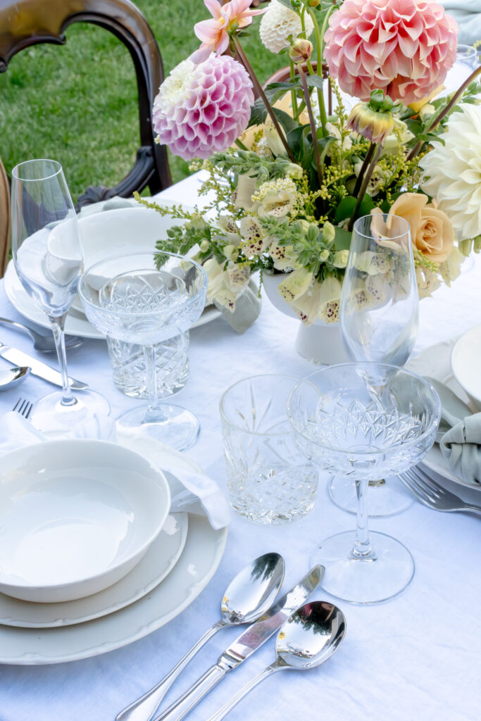 The image shows an outdoor dining area with a flower-adorned table and chairs arranged around it.