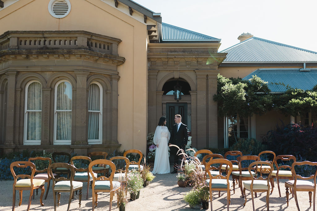 The photo depicts a man and woman in wedding attire standing in front of a door.