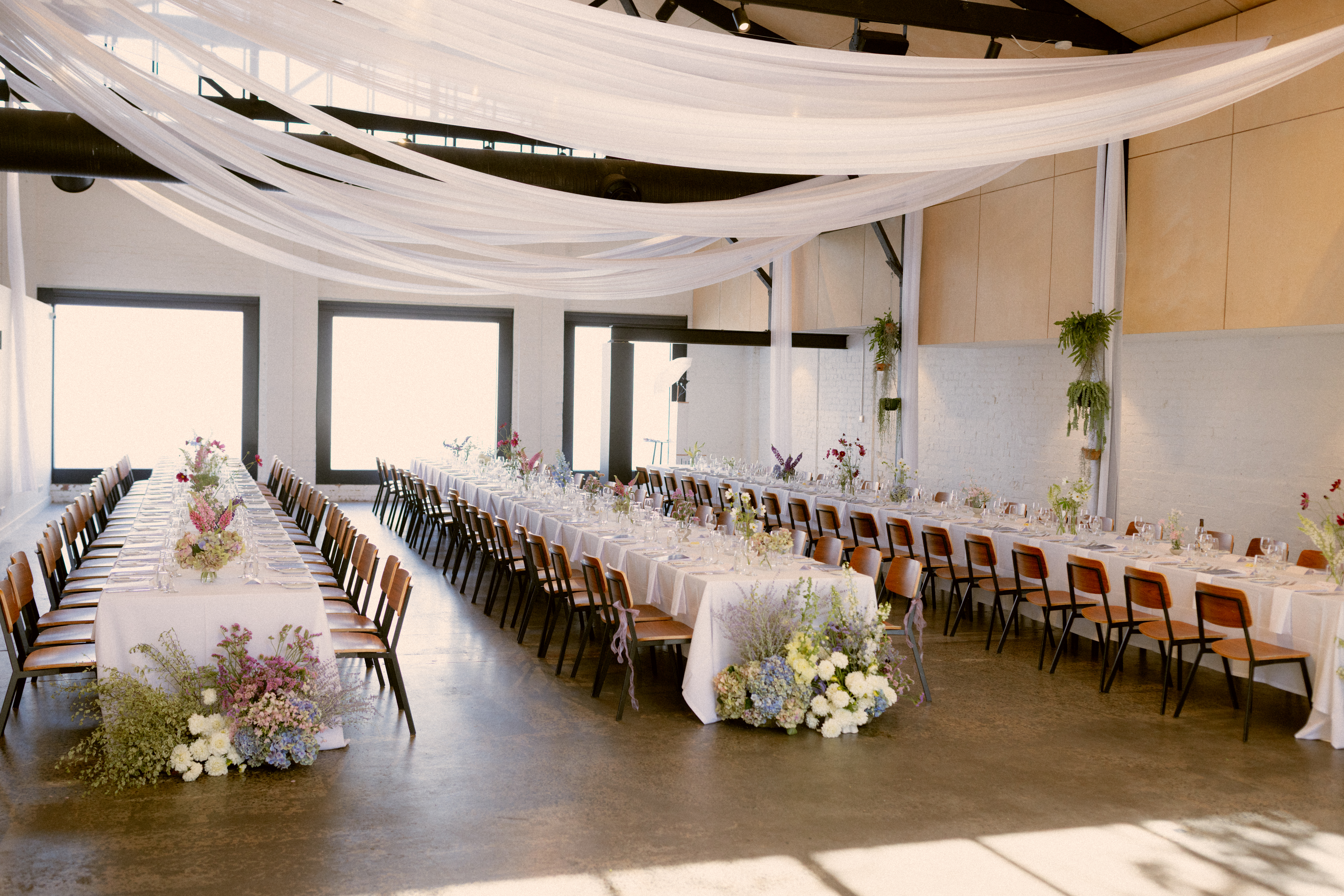 Modern Melbourne wedding reception with long tables, whimsical Australian flowers, and soft white draping.